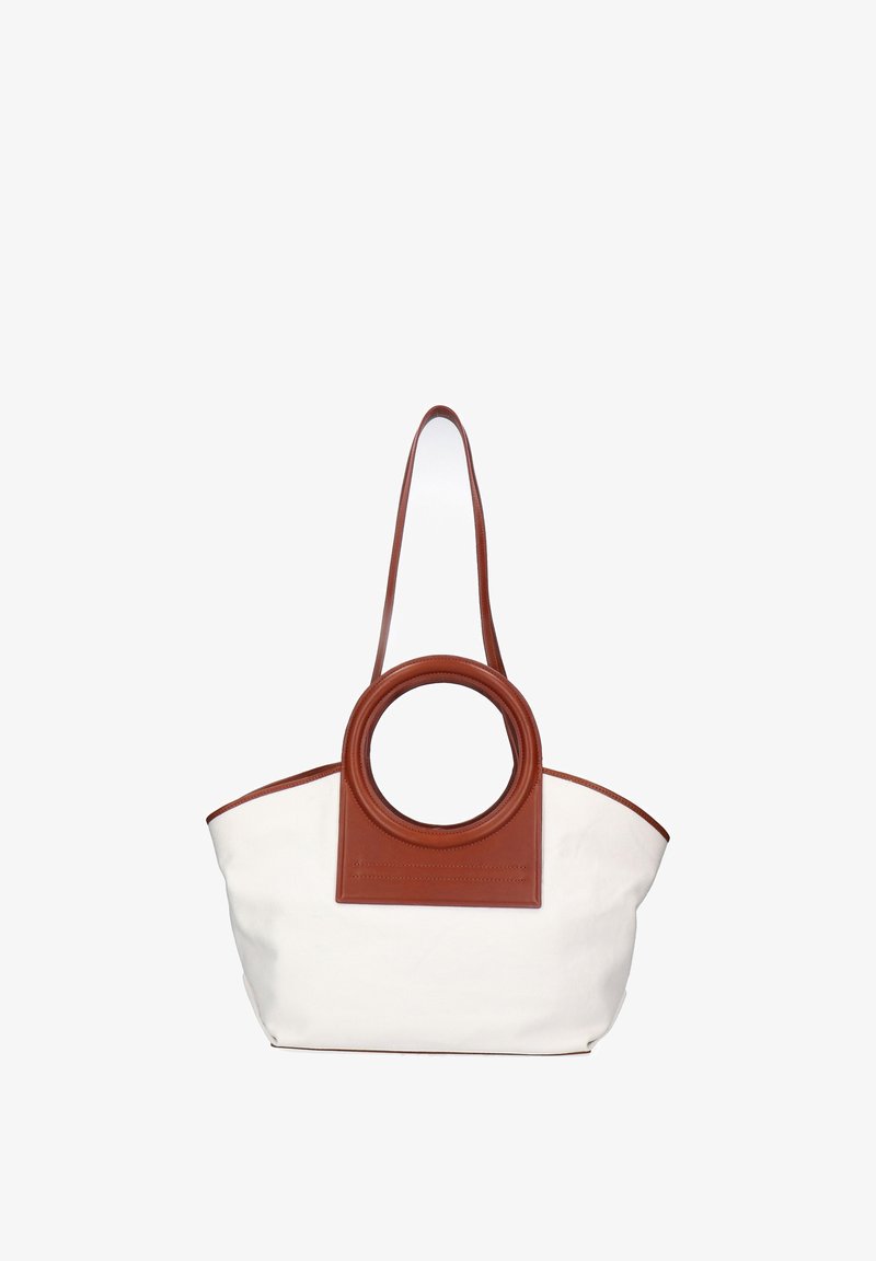 Bolso tote blanco con un asa grande circular de cuero marrón y una larga correa marrón para el hombro sobre fondo blanco.