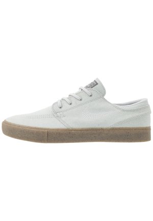 Niskie jasnoszare zamszowe sneakersy z białymi sznurowadłami, przeszywanym logo Nike i gumową podeszwą.