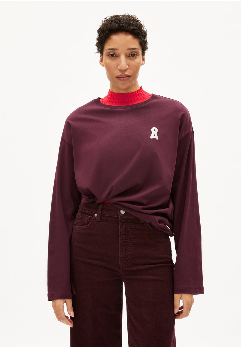 Bordeaux lange mouwen t-shirt met een ronde hals en een wit lintlogo op de borst, gecombineerd met donkerbordeaux corduroy broek.