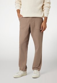 Beige bomulds cargo bukser med to forlommer, afslappet pasform og lige ben. Båret med hvide sneakers.