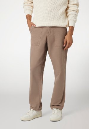 Beige katoenen cargobroek met twee voorzakken, ontspannen pasvorm en rechte pijpen. Gecombineerd met witte sneakers.