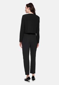 Black cropped blazer and matching tapered pants. The outfit features a clean design with a smooth texture, paired with black high-heeled shoes.