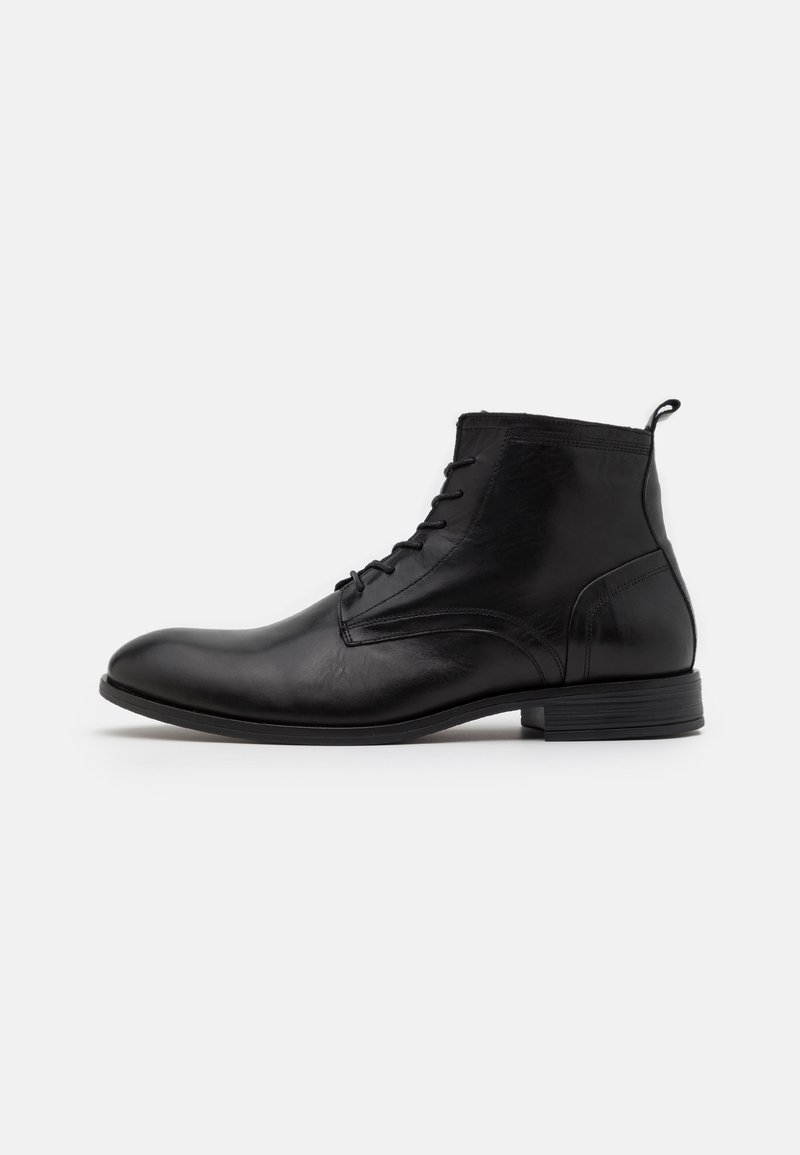 Botín de cuero negro hasta el tobillo con un acabado suave, diseño con cordones, punta redondeada y mínimas embellishments, con un tacón bajo y apilado.