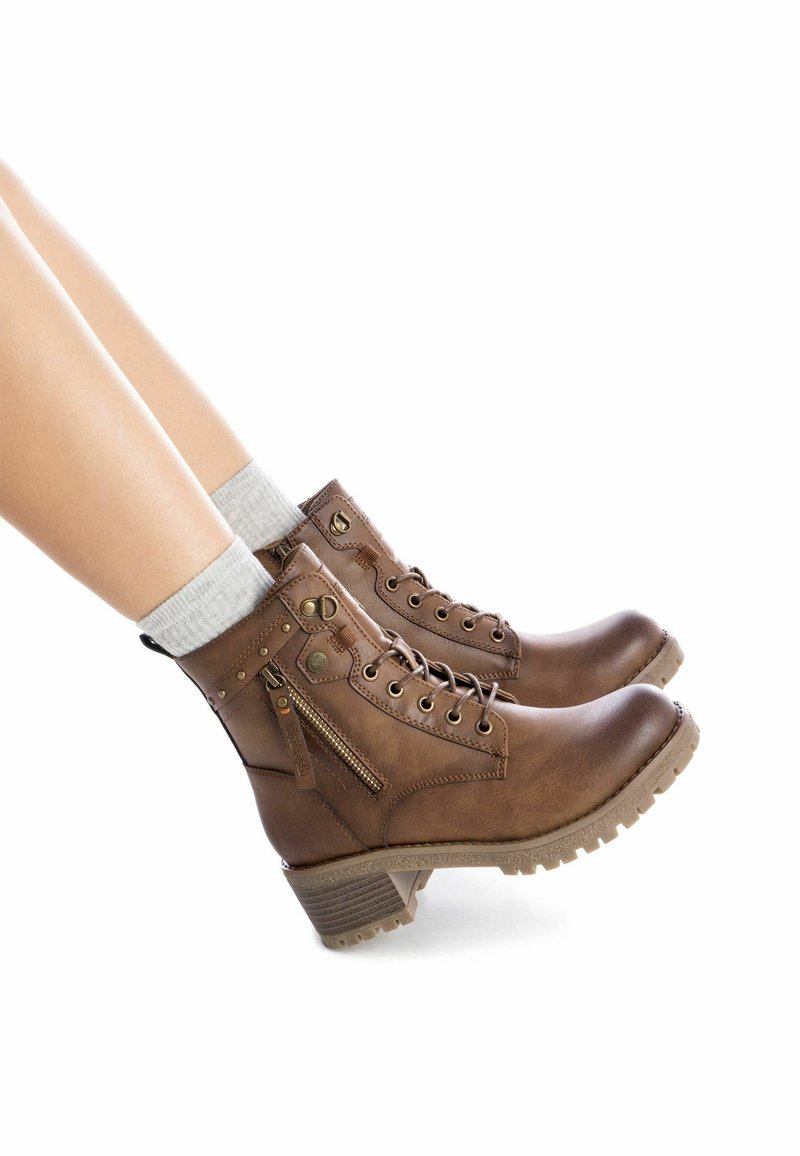 Botas de tobillo de cuero marrón con una suela resistente, cordones y una cremallera lateral; cuentan con acentos metálicos y un acabado texturizado.