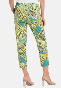 Hose mit einem bunten Blatt- und geometrischen Muster in Blau, Grün und Gelb. Kurzes Design mit weichem Material und elastischem Bund.