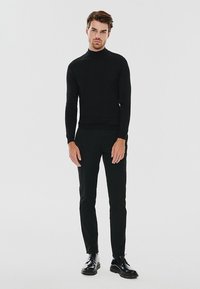 Czarny sweter golf z dopasowanymi czarnymi spodniami i błyszczącymi czarnymi butami, cechujący się eleganckim, minimalistycznym designem i miękką teksturą.