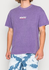 Lila kortärmad t-shirt med rund hals, med en vit och röd "MOUNT FUJI" grafik på bröstet. Mjuk, avslappnad tyg.