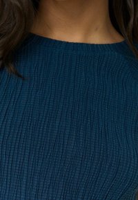 Mørkeblå struktureret top med et ribbet mønster. Rund halsudskæring og korte ærmer, lavet af et blødt, let materiale.