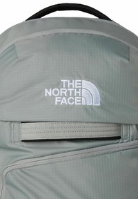Grijze nylon rugzak met logo-borduring in het wit. Gedetailleerd met een horizontale webbingriem en een getextureerd rasterpatroon.
