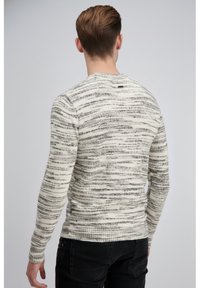 Kremasto-sivi pulover iz pletenine s črtami, dolgimi rokavi, rebrastimi manšetami in robom. Ima okrogel izrez in majhno etiketo na zadnji strani.