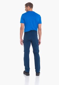 Blaues kurzärmliges Hemd und marineblaue Hose mit einem eleganten Design. Die Hose verfügt über Reißverschlüsse und einen geraden Schnitt. Schwarze Schuhe runden das Outfit ab.