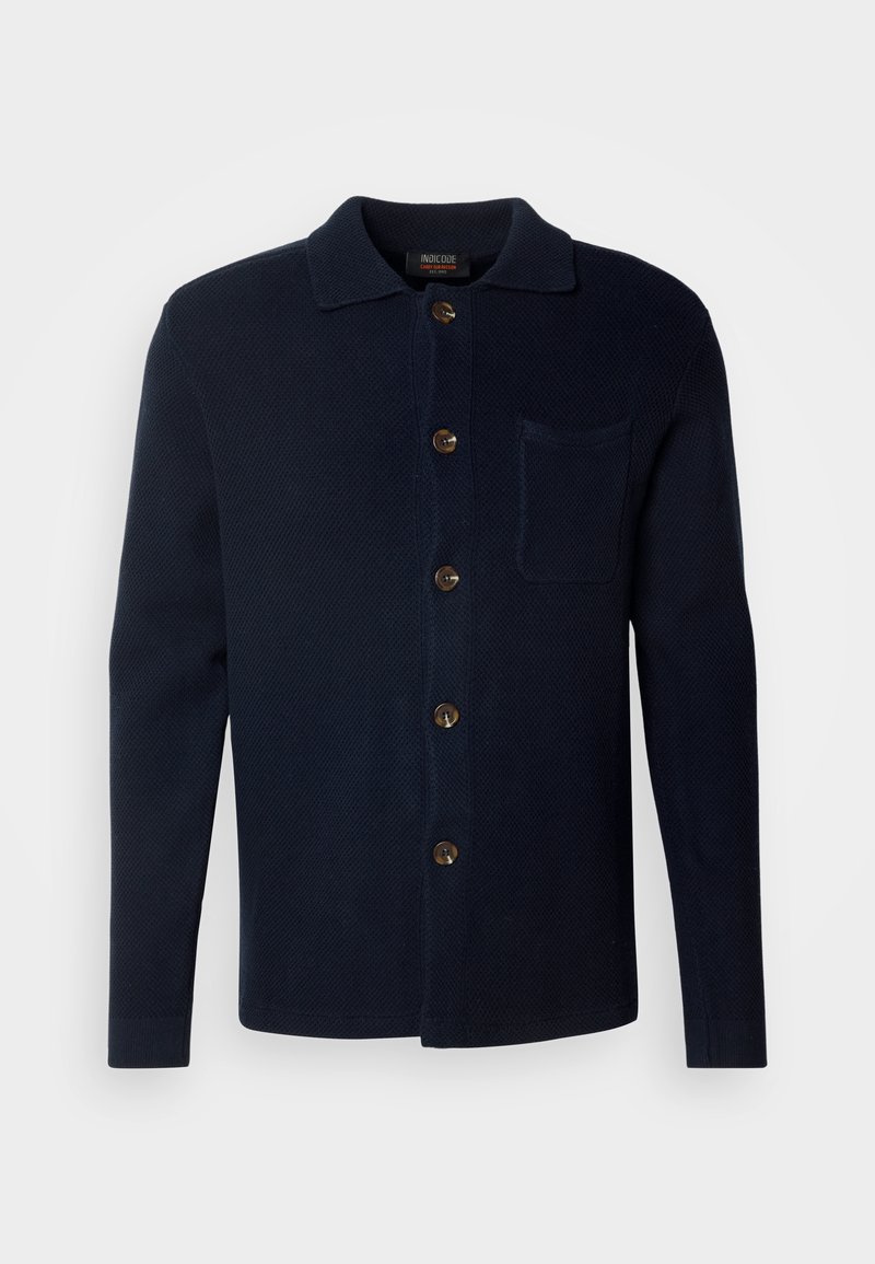 Chemise bleu marine à boutons, en tissu texturé, avec un col, une poche avant et des boutons marron.