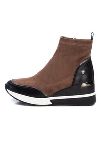 Botín de ante en marrón con punta y tacón de charol negro, entresuela blanca y acentos texturizados, que presenta un detalle de logo metálico.