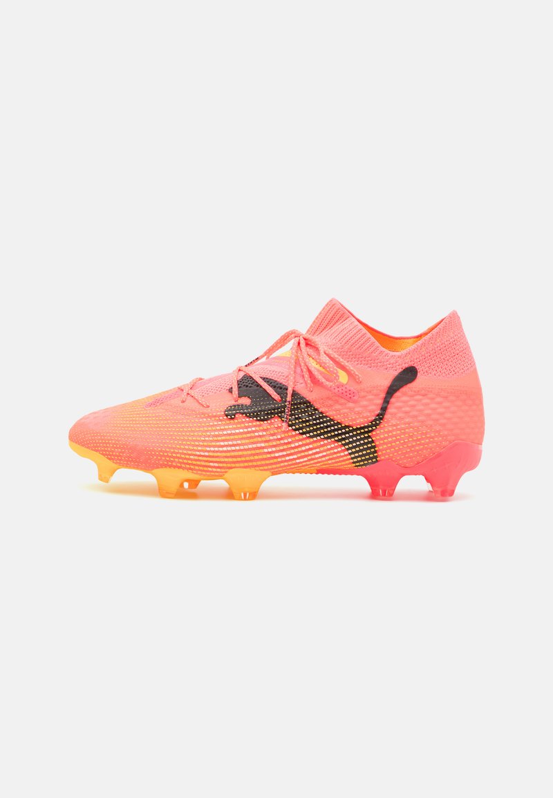 Helle pinke Fußballschuhe mit einem strukturierten Mesh-Obermaterial, schwarzem Logo-Detail und einem Farbverlauf von Orange zu Gelb an der Sohle. Mit vorderer Schnürung und niedrigem Knöchel.