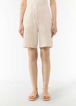 Light beige linen shorts with a relaxed fit, folded hem, front pockets, and a zipper closure. Paired with beige strappy sandals.