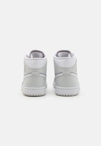 Vysoké tenisky z světle šedé kůže s bílými akcenty. Mají polstrovaný límec, šité detaily a texturovanou gumovou podrážku.
