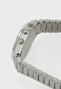 Edelstahl-Uhr mit einem strukturierten grauen Armband, grünen Akzenten und zwei Druckknöpfen an der Seite, glattem Lünette und rundem Gehäuse.