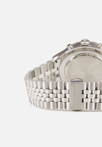 Stainless steel watch with a linked band. Features a polished finish, round case, and a closure with engraved brand name.