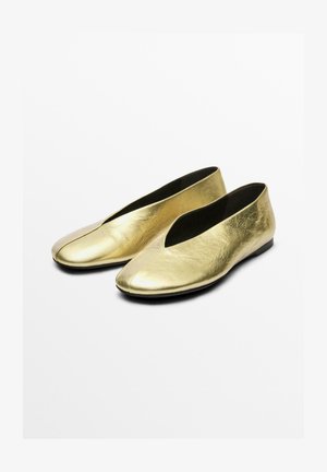 Guldläderballetskor med en slät yta, en v-formad öppning framtill och en låg, platt svart sula.