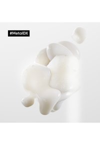 Un liquide blanc et brillant avec des bulles, présentant une forme lisse et organique. Une petite bulle flottante accompagne la formation principale sur un fond clair.