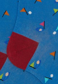 Calzini blu con un motivo di triangoli colorati, cerchi e barche a vela, con talloni rossi a contrasto e materiale leggero e morbido.