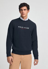 Sudadera azul marina confeccionada en una mezcla de algodón, con cuello redondo, puños de canalé y el logotipo "POLO CLUB ESTABLISHED 2012" en blanco y rojo.
