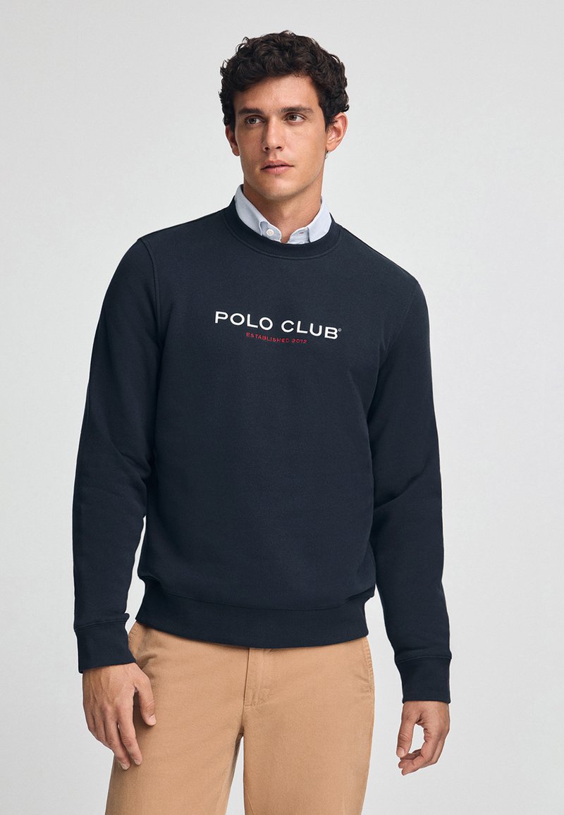 Sudadera azul marina confeccionada en una mezcla de algodón, con cuello redondo, puños de canalé y el logotipo "POLO CLUB ESTABLISHED 2012" en blanco y rojo.