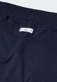 Pull bleu marine à col rond fabriqué en tissu doux et léger. Présente un col et un ourlet côtelés. Étiquette d'entretien visible à l'intérieur.