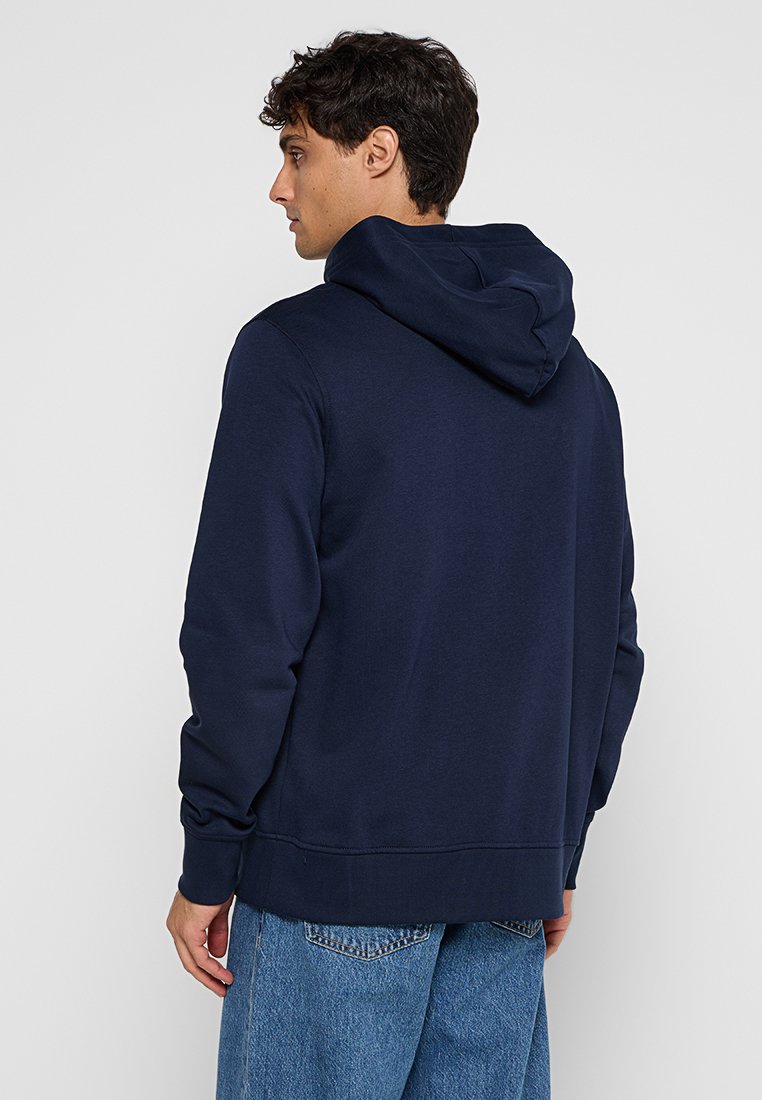 Marinblå hoodie med en känguruficka och dragsko på huven, med ribbade mudd och nederkant. Slät tyg med en avslappnad passform.