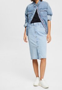 Vaaleansininen farkkuhame, jossa on etunappikiinnitys, ribbed-vyötärö ja suora leikkaus, yhdistettynä farkkutakkiin ja valkoisiin tennareihin.