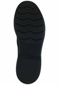 Semelle de chaussure en caoutchouc noir avec des motifs de grip texturés, présentant un léger design en vagues et des trous de ventilation pour la respirabilité. Marquée "GEOX."