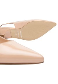 Scarpa con tacco alto in pelle verniciata color nude, con punta affilata e cinturino alla caviglia, dotata di suola in gomma texturizzata e logo sulla soletta.