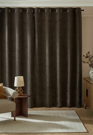 Dunkelbraune, strukturierte Vorhänge, die an einer schwarzen Metallstange in einem gemütlichen Raum mit gemustertem Sessel, Holztisch, Lampe, Teppich und Holzschrank mit Vase hängen.
