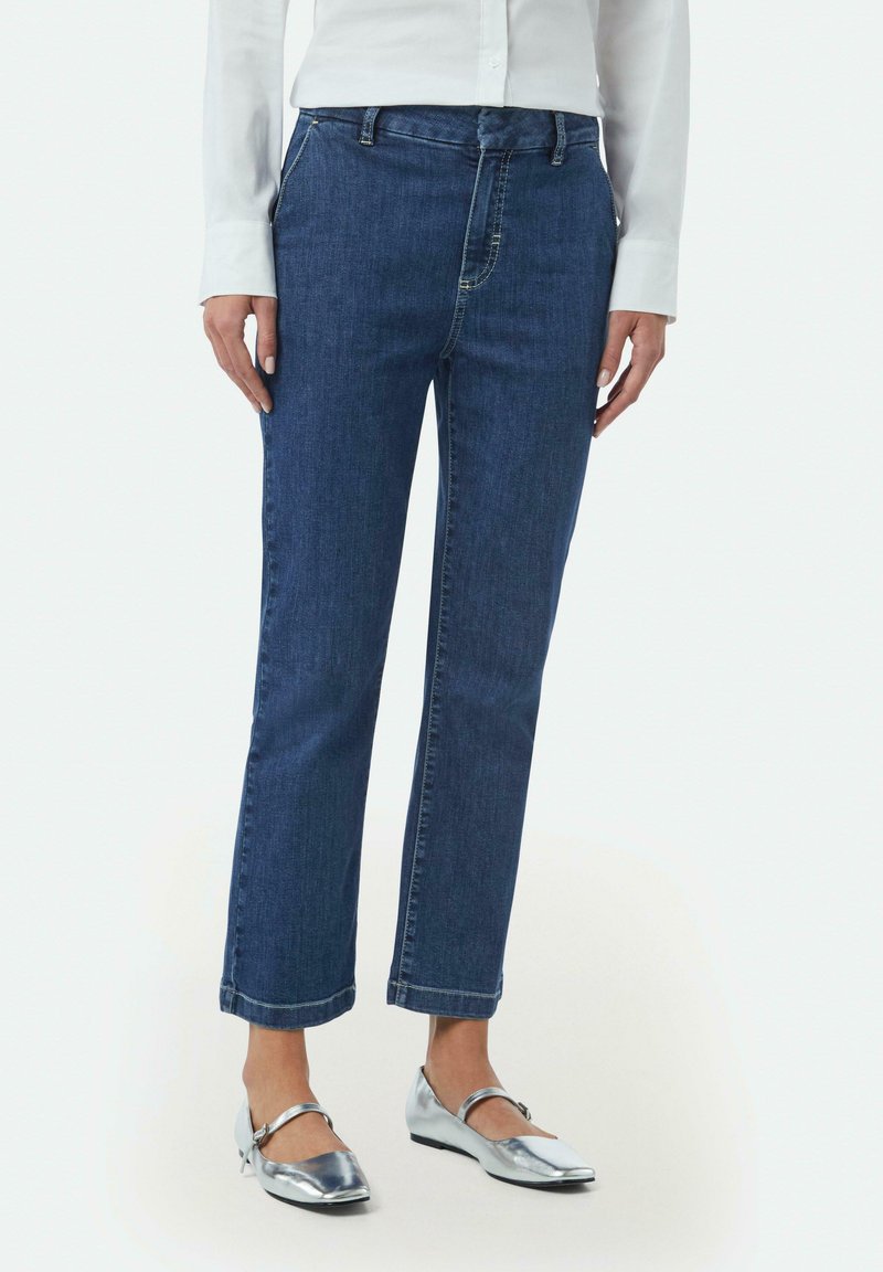 Donkerblauwe denim jeans met een recht model, voorzien van voorzakken en een knoopsluiting. Accentuatie met opgerolde zoom voor een casual uitstraling.