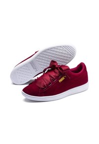 Burgundy suede sneakers with wide satin laces, white rubber sole, gold logo accent, and textured outsole for grip and stability.