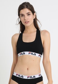 Top sportivo nero con scollatura quadrata e ampia fascia elastica bianca con il logo FILA in rosso e nero. Materiale in cotone morbido e morbido.