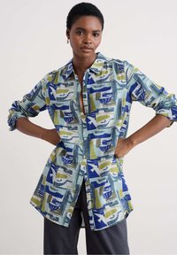 Button-up shirt featuring a colorful abstract pattern in blue, green, and white, with a relaxed fit and rolled sleeves.