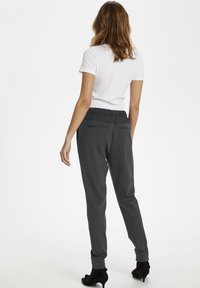 Grå jersey joggerbyxor med elastisk midja, bakfickor och smalnande ben, i kombination med en figurnära vit t-shirt och svarta klackar.