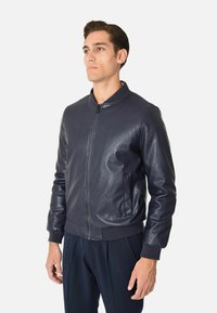 Giubbotto bomber in pelle blu navy con zip frontale, polsini a coste, tasche laterali e una texture liscia. Design semplice e moderno.
