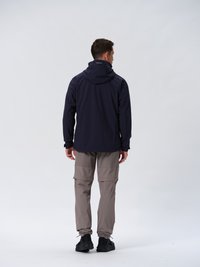 Veste imperméable navy avec capuche, associée à un pantalon cargo beige avec poches latérales, sur un fond neutre.