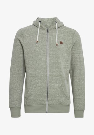 Green zip-up hoodie made of textured fabric. Features a drawstring hood, two front pockets, and a small logo patch on the chest.