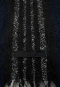 Eșarfă din lână cu un design în dungi de culoare albastru închis, negru și alb, având un finisaj moale și texturat; eticheta neagră este inscripționată cu "CLASIC. MODERN. AL TĂU."