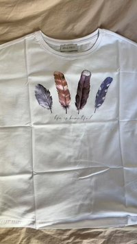 Bijela majica s grafikom pet perja u raznim bojama (ljubičasta, smeđa, siva) s natpisom "život je lijep" ispod.
