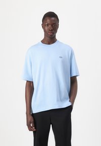 T-shirt en coton bleu clair avec un col rond et des manches courtes. Avec un petit logo brodé sur la poitrine gauche.