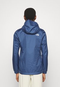 Navyblauer wasserdichter Anorak mit Kapuze, elastischen Bündchen und dem North Face-Logo an der oberen Rückseite. Glattes, leichtes Gewebe.