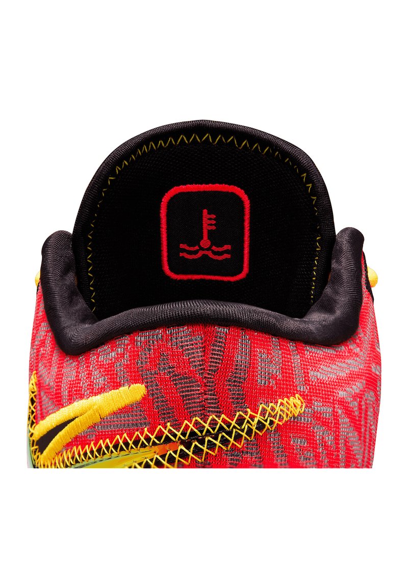 Baskets de sport rouges et noires avec un tissu texturé, accents jaunes et un col arrondi. Présente un logo rouge sur un fond noir.