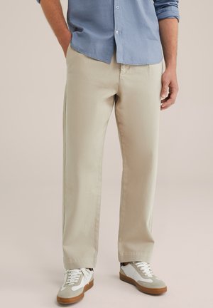 Chinos beige con un corte recto, elaborados en un suave tejido de algodón. Combinados con zapatillas blancas y grises para un look casual.