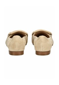 Mocasines de ante beige con un tacón bajo, punta redonda y lados abiertos. Presentan una textura suave y un diseño minimalista para mayor comodidad.
