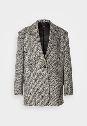 Blazer preto e branco em padrão houndstooth texturizado, com lapelas com recorte, um botão preto único e forro preto acolchoado. Mangas longas, ajuste descontraído.