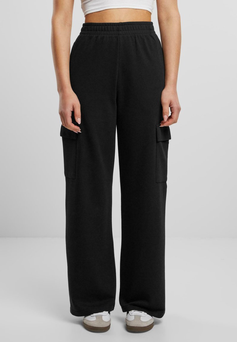 Schwarze Sweatpants mit lockerer Passform, elastischem Bund und zwei Seitentaschen im Cargo-Stil. Weicher Stoff mit glatter Textur.